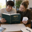 students studying FSI's Study Guide, the "Big Green Book", with the MFT Models Comparison Chart placed on the table and another student holding the MFT Glossary Flashcards